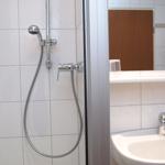 Dusche mit Handbrause und Waschbecken mit Wasserhahn