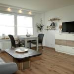 Wohnzimmer mit Esstisch, Sofa, Fernseher und Holzboden.