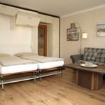 Zimmer mit Schlafcouch, Wohnbereich und Holzboden.