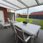 Deck with table, chairs, and awning over green lawn.