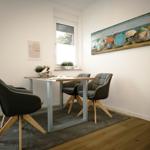 Dining room with table, four chairs, and wall art featuring umbrellas.