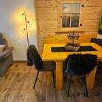 Essbereich mit Holztisch, Bänken und Stühlen. Wohnbereich mit Sofa und Wandbild.