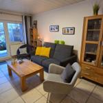 Wohnzimmer mit Sofa, Sessel und Glasvitrine. Durchgang zum Außenbereich mit Schnee.