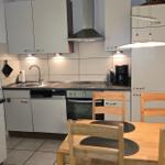 Küche mit Essbereich, Holztisch, Stühle, Kühlschrank, Herd und Spüle.