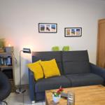 Ein Wohnzimmer mit grauem Sofa, gelben Kissen und Holztisch.