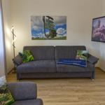 Ein Wohnzimmer mit grauem Sofa, Fernseher und Wandbild.