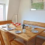 Esszimmer mit Holztisch, Bänken und Fensterblick auf Dach