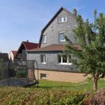 Haus mit Garten und Trampolin. Blick auf das Grundstück mit Baum und Rasen.
