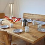 Holztisch mit Platz für sechs Personen, Geschirr und Kaffeekanne