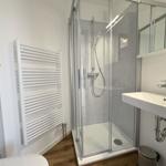Badezimmer mit Dusche, Waschbecken und Heizung.