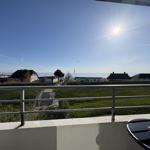 Balkon mit Blick auf den Strand und das Meer unter strahlendem Sonnenschein.