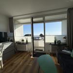 Wohnzimmer mit Sofa, Fernseher und Balkon mit Meerblick.