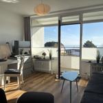 Wohnzimmer mit Balkonblick auf Meer. Möbel und Dekoration sichtbar.