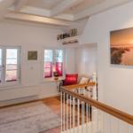 Wohnbereich mit Holzboden, TV, Fenstern und Wandbild