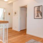 Helle Wohnung mit Holzboden, Wandbild und Fernseher auf Schrank