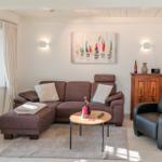 Ein Wohnzimmer mit braunem Sofa, schwarzer Ledercouch und Holzkommode.