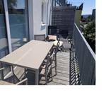 Terrasse mit Tisch, Stühlen und Liegen. Holzdecke und Sicht auf Grünflächen.