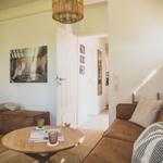Wohnzimmer mit Sofa, runden Tisch und Wandbild. Durchgang zur Küche.