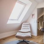 Dachgeschosszimmer mit Sitzgelegenheit und Dachfenster. Holzboden und offene Tür.