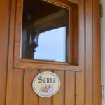 Holztür mit Sichtfenster und Sauna-Schild.