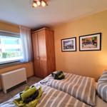 Schlafzimmer mit Bett, Kleiderschrank und Fenster. An der Wand hängen zwei Bilder.