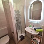 Badezimmer mit Dusche, Waschbecken und Toilette. Spiegel mit Beleuchtung und Handtücher.
