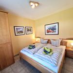 Schlafzimmer mit Doppelbett, Holzmöbel und Wandbildern.