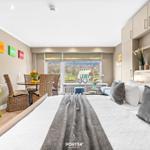 Bedroom with large bed, window view, and dining area with chairs.