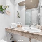 Bathroom with sink, mirror, shower, and towel rack.