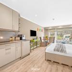 Kitchen with worktop, bedroom with bed and window view.