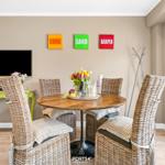 Round table with four chairs, wall art and TV. Window with view outside.