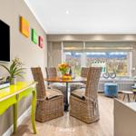 Dining room with table, chairs, and TV. Window with view of garden.