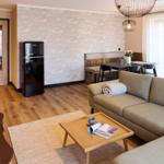 Wohnzimmer mit Sofa, Esstisch, Kühlschrank und Holzboden.