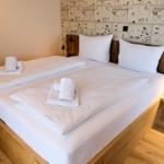 Ein Bett mit weißen Laken und Handtüchern, Holzrahmen und Wand mit Zeichnungen.