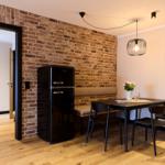 Essbereich mit Tisch, Stühlen und Kühlschrank an Backsteinwand.