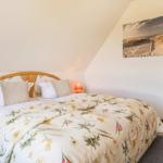 Schlafzimmer mit Doppelbett, floraler Bettwäsche und Wandbild an der Schrägwand.