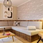 Ein Wohnbereich mit Sofa, Tisch und Lampen. Wand mit Tapete und Bild.