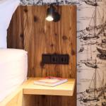 Schlafzimmer mit Holzkopfteil, Nachttisch und Segelyacht-Wandtapete.