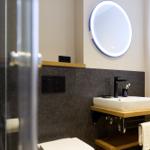 Badezimmer mit Dusche, Waschbecken und beleuchtetem Spiegel.