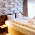 Schlafzimmer mit Bett, Wandtapete mit Schiffsmotiven und Fenster mit Vorhängen.