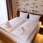 Doppelbett mit weißen Bettwäsche und Fischmotiv-Wandtapete.