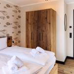 Schlafzimmer mit Bett, Holzschrank und Fischmotiv-Wandtapete. Durchgang zur Küche.