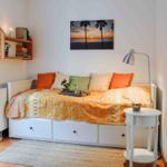 Schlafzimmer mit Bett, Kissen und Wandbild. Neben dem Bett steht ein Nachttisch.