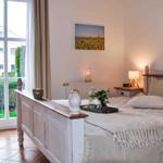 Schlafzimmer mit Bett, Nachttisch und Fenster zur Außenansicht.
