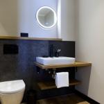 Badezimmer mit Waschbecken, Toilette und runden Spiegel.