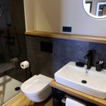 Bad mit Dusche, Toilette und Waschbecken auf Holzunterlage
