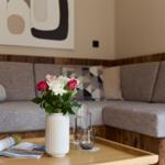 Ein Wohnbereich mit Sofa, Tisch und Blumenarrangement.