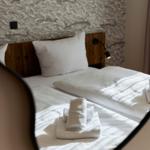Doppelbett mit weißen Laken und gefalteten Handtüchern im Spiegel