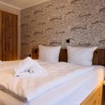 Doppelbett mit weißen Bettwäsche, Holzgestell und Fischmotiv-Wandtapete.