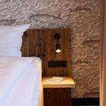 Schlafzimmer mit Holz-Kopfteil, Wand mit Meerestier-Motiv und Nachttisch mit Buch.